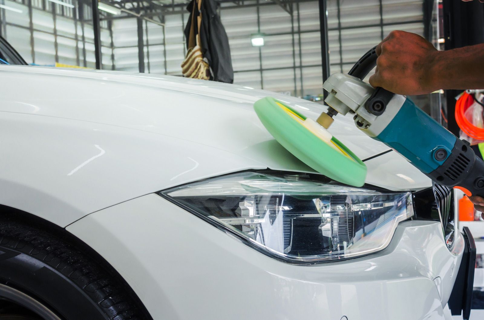 Red car on a white tow truck, parked on a road with green trees in the background.