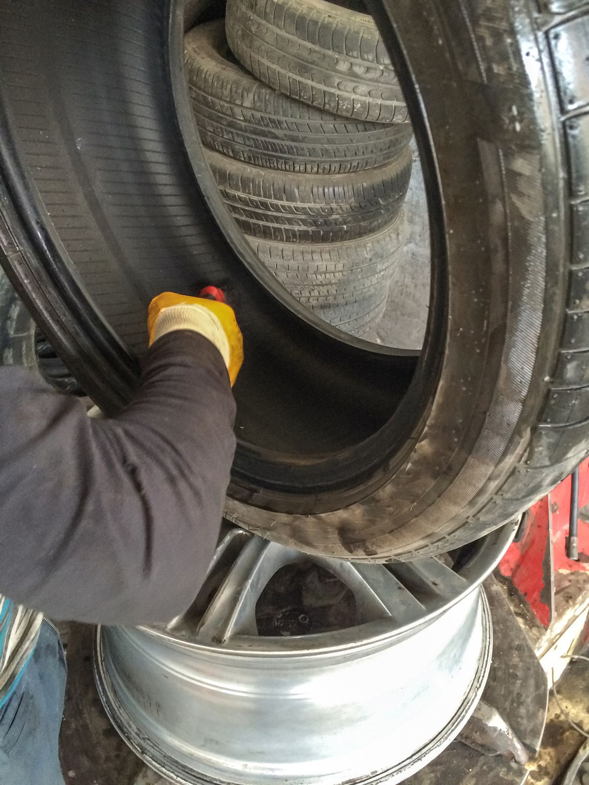 Red car on a white tow truck, parked on a road with green trees in the background.