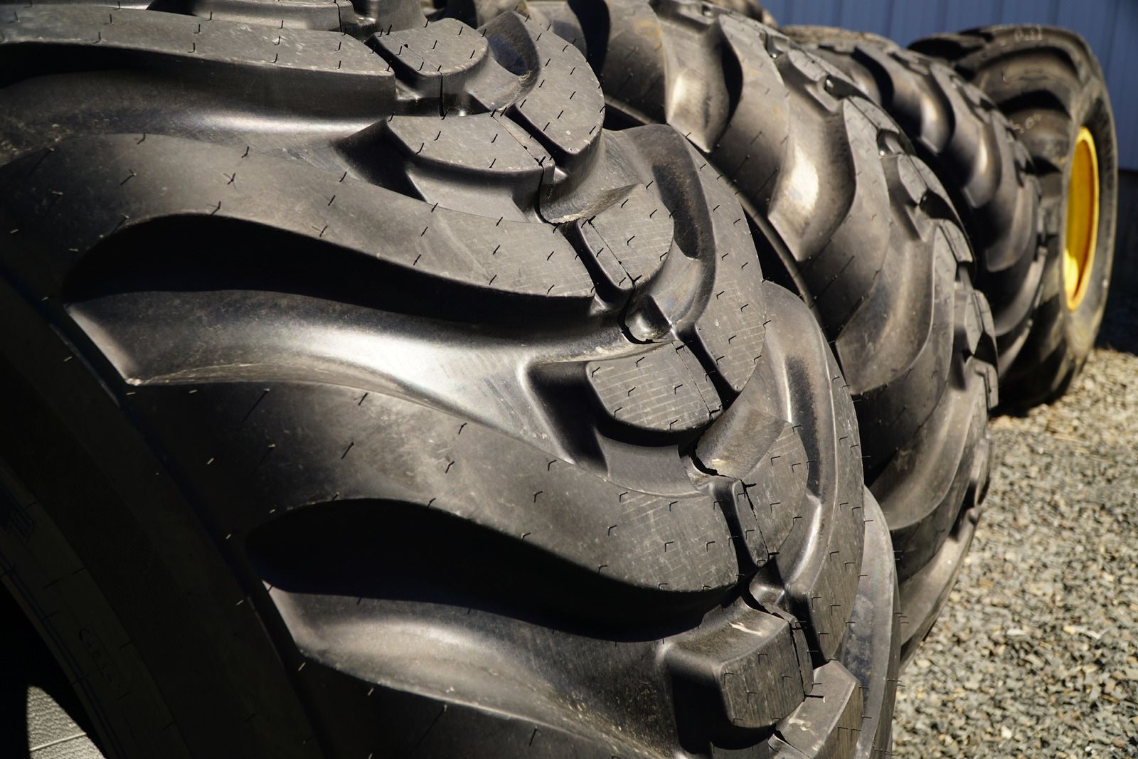 Yellow tow truck carrying a black car on a sunny street.