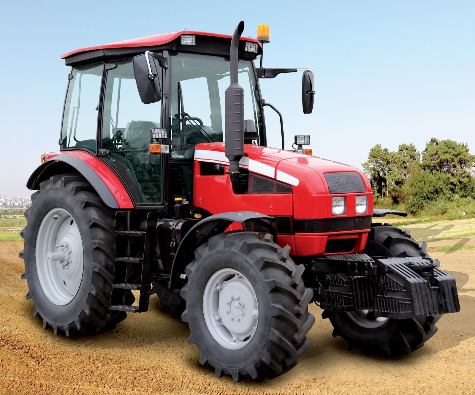 Red car on a white tow truck, parked on a road with green trees in the background.