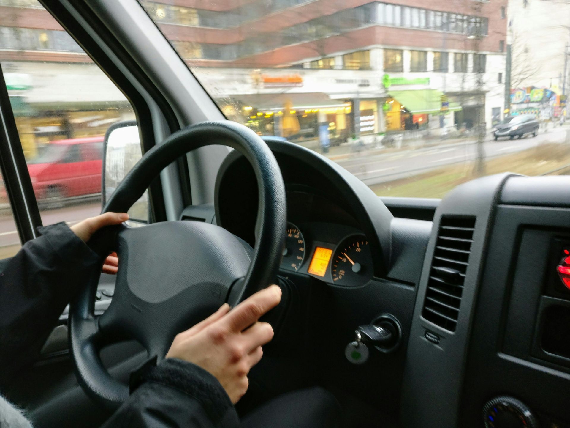 A person is driving a van with their hands on the steering wheel