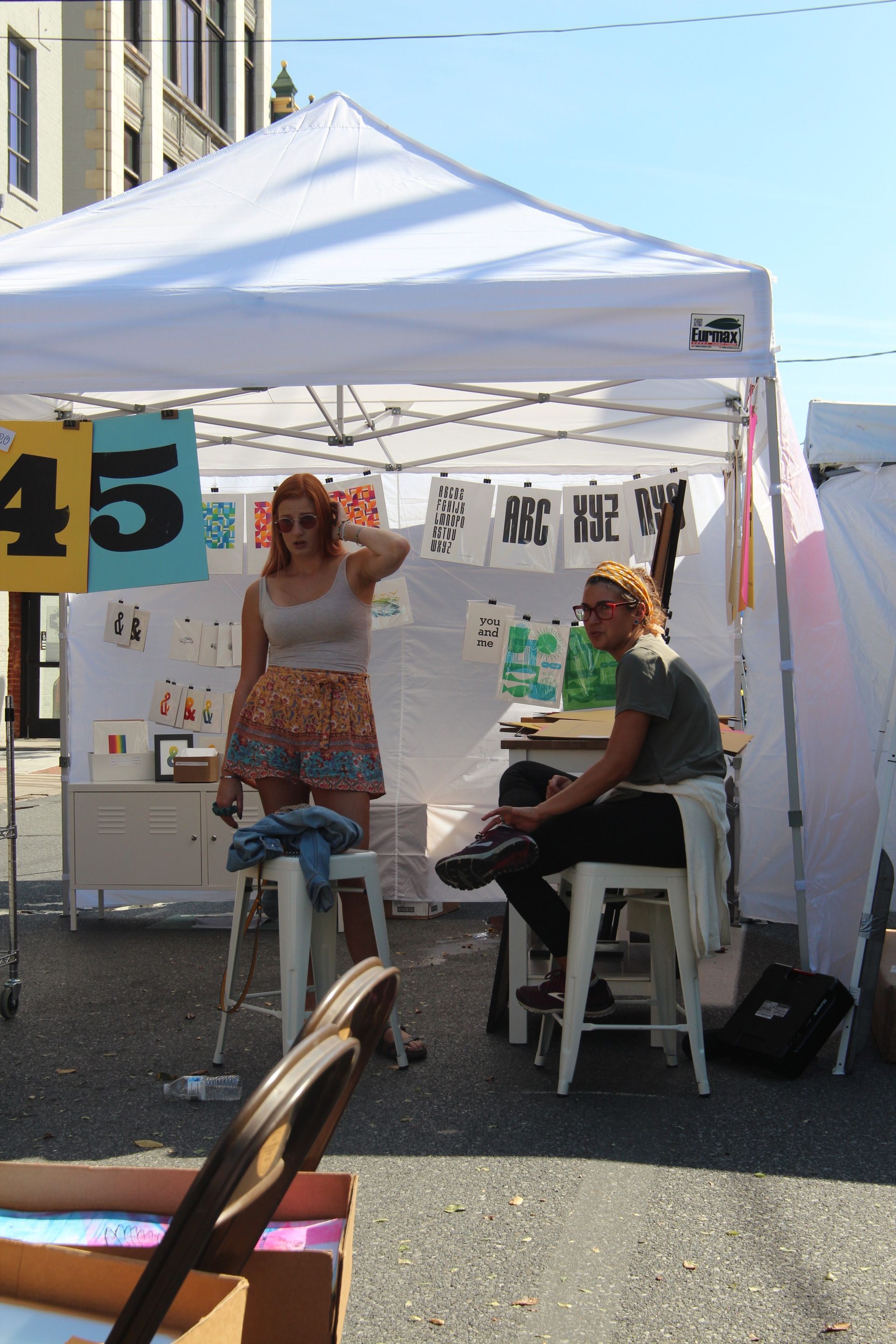 Two people sitting under a tent with a sign that says 45
