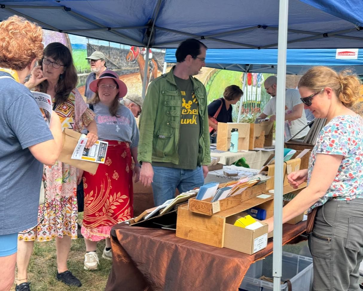 A group of people are standing around a table under a tent.
