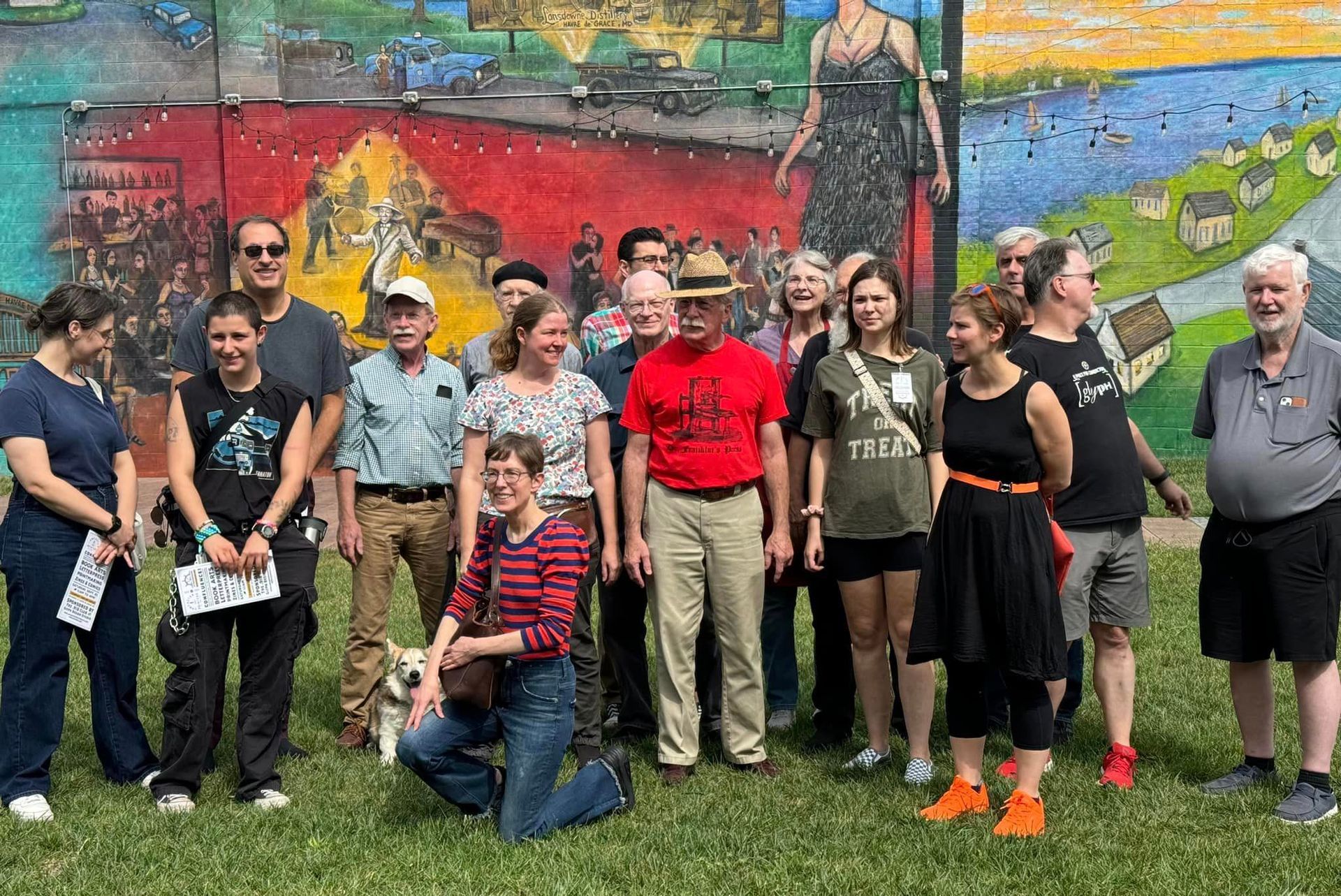 A group of people are posing for a picture in front of a mural.