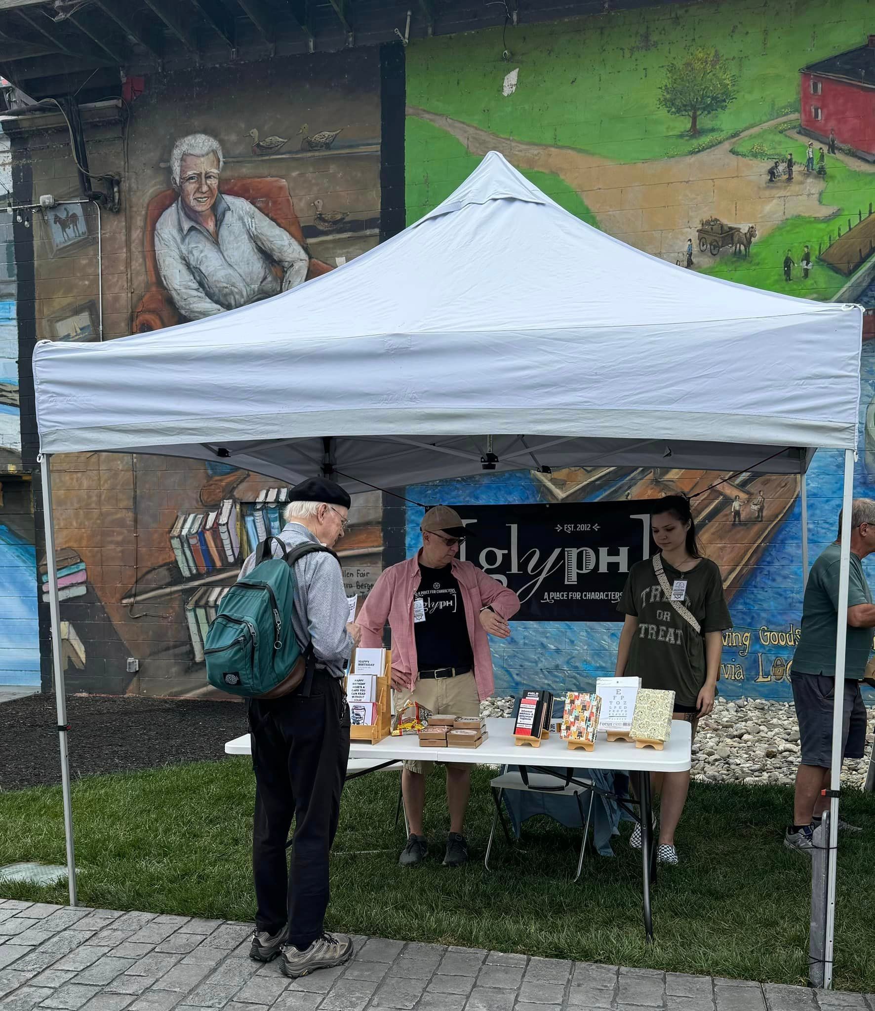 A group of people are standing under a white tent.