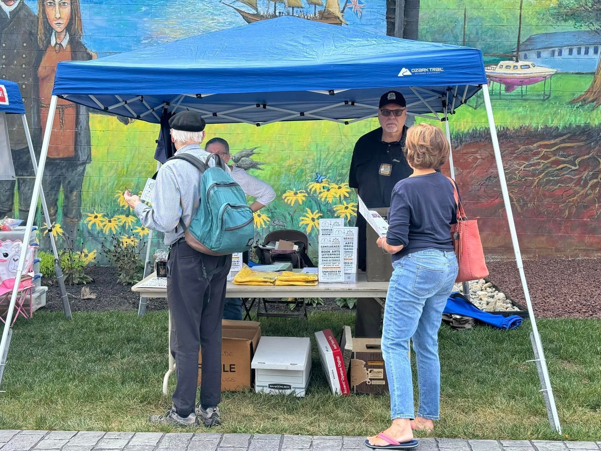A group of people are standing under a tent talking to each other.