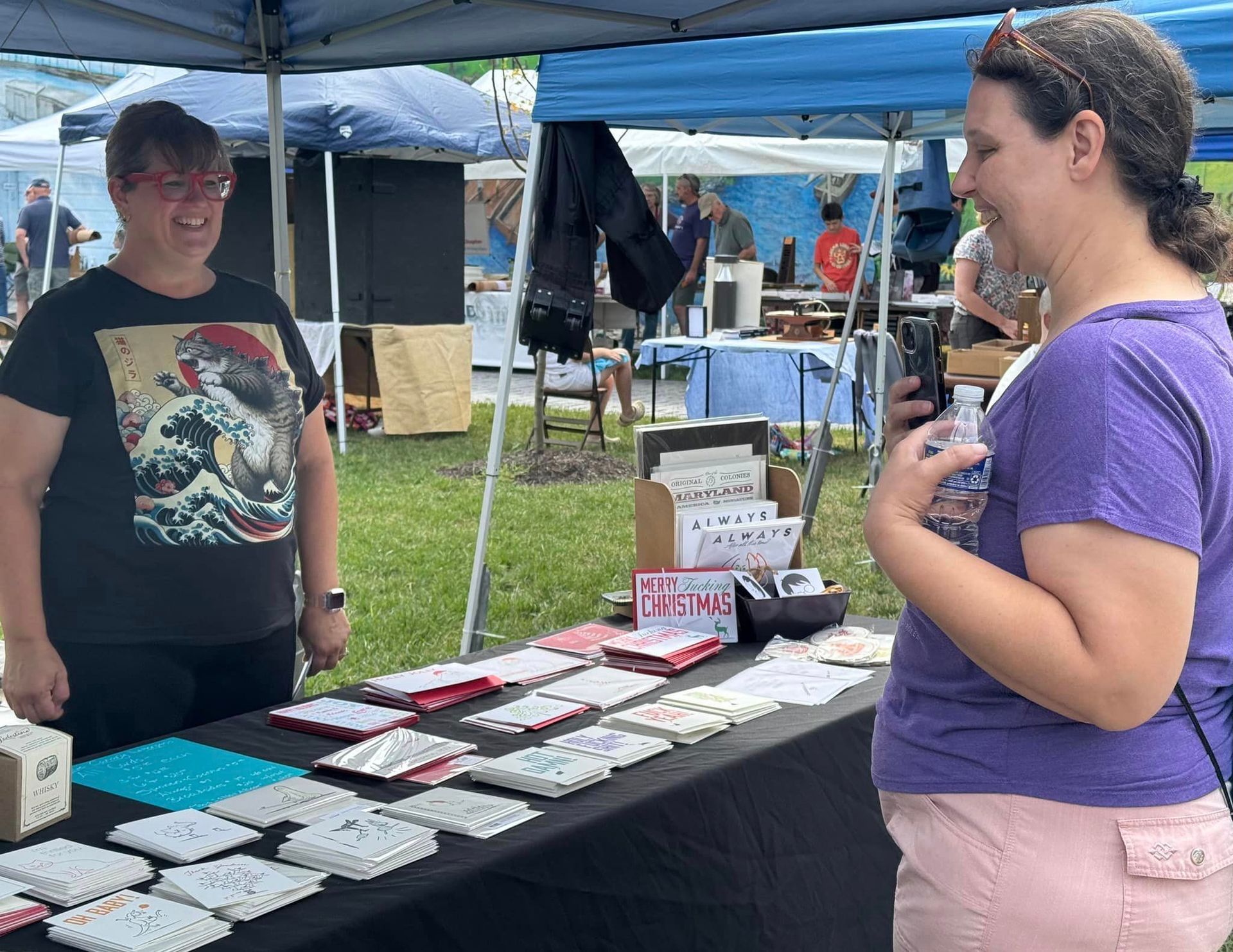 A woman in a purple shirt is standing next to a woman in a black shirt.