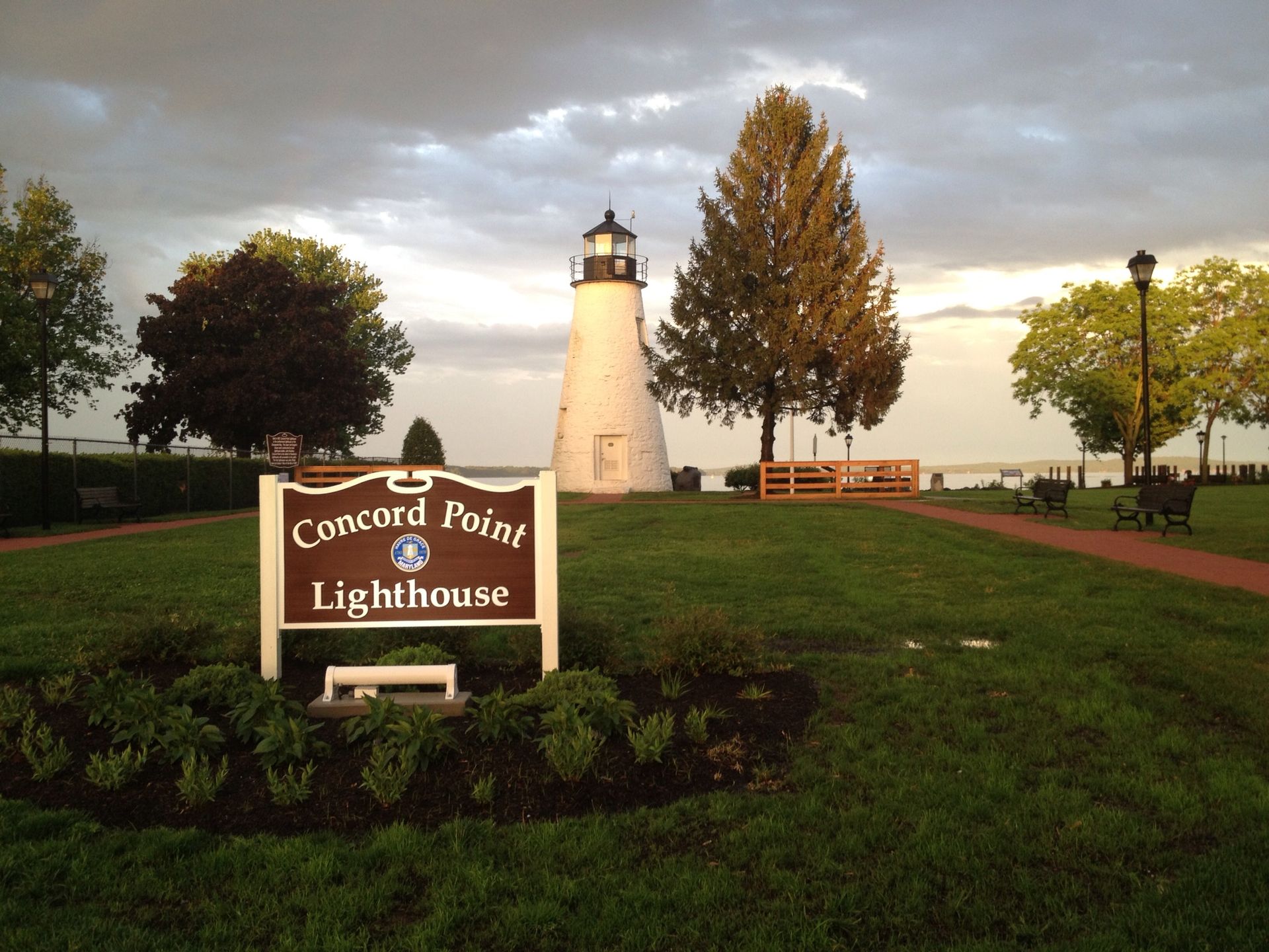 A lighthouse in a park with a sunset in the background.