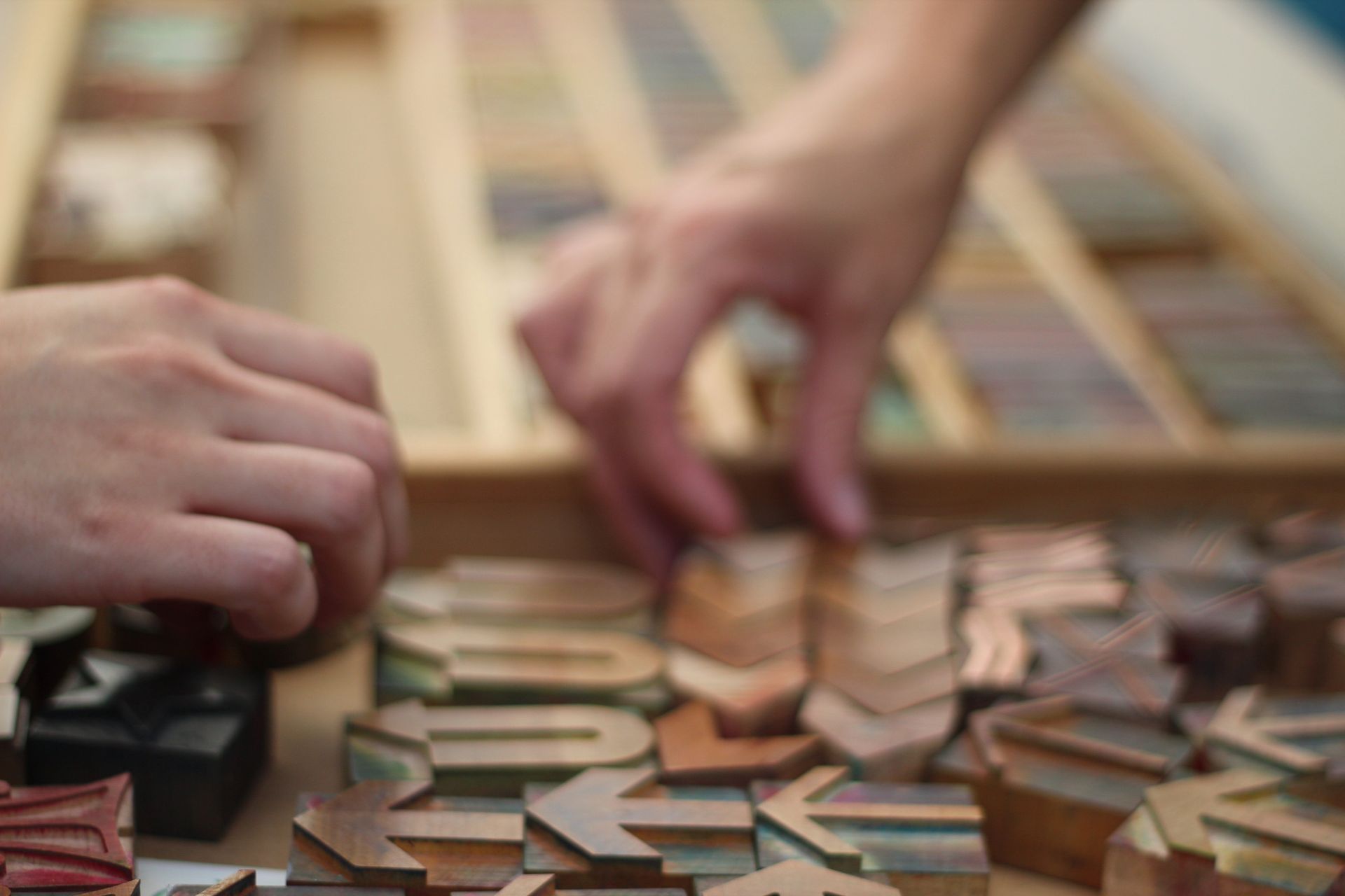 A person is playing a game with wooden letters on a table.