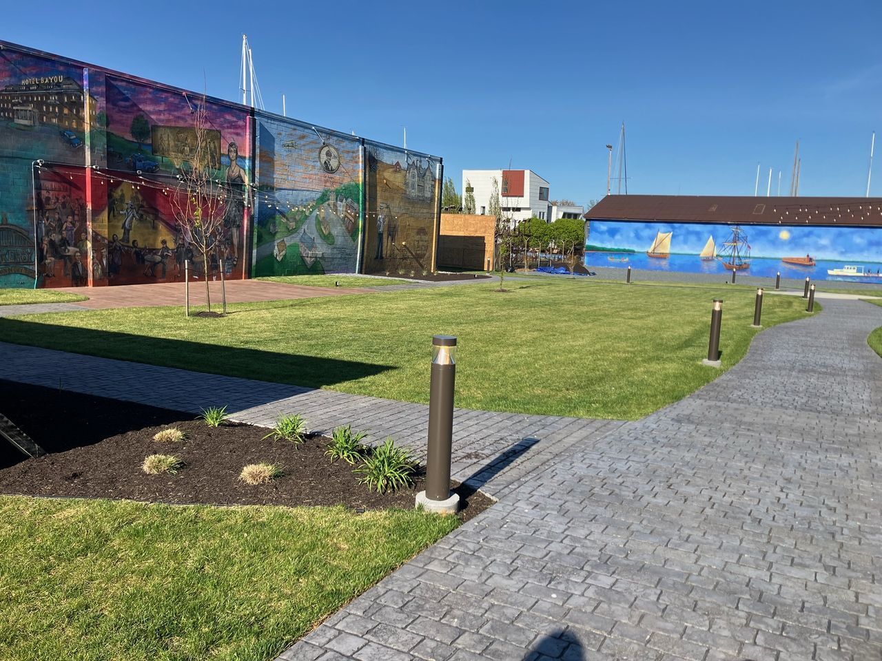 A brick walkway leading to a large mural on the side of a building.