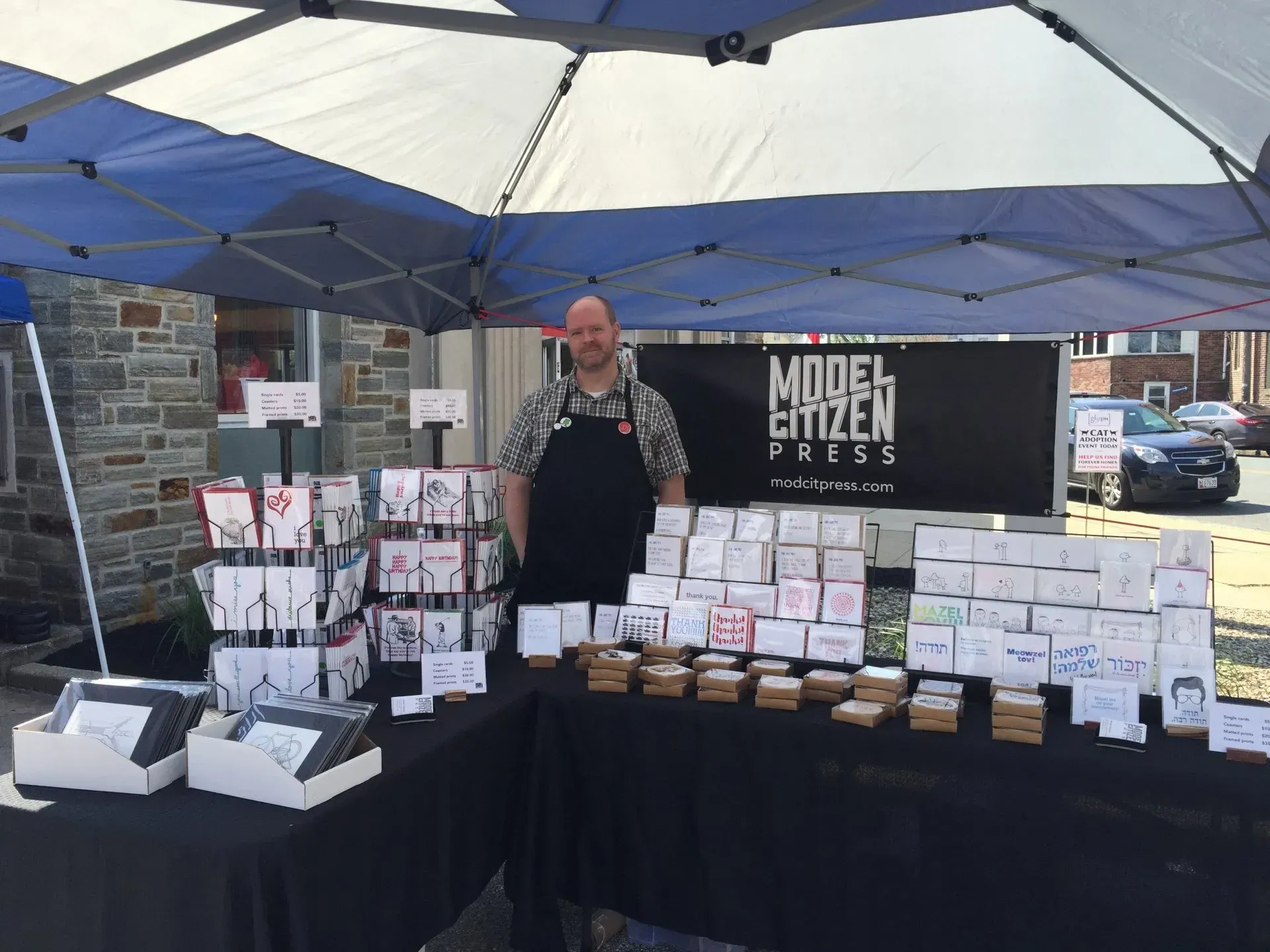 A man is standing in front of a model citizen press tent