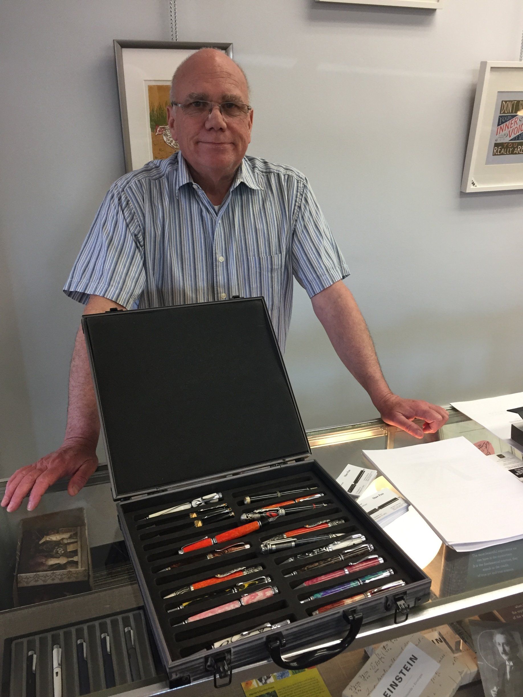A man is standing in front of a case filled with pens.