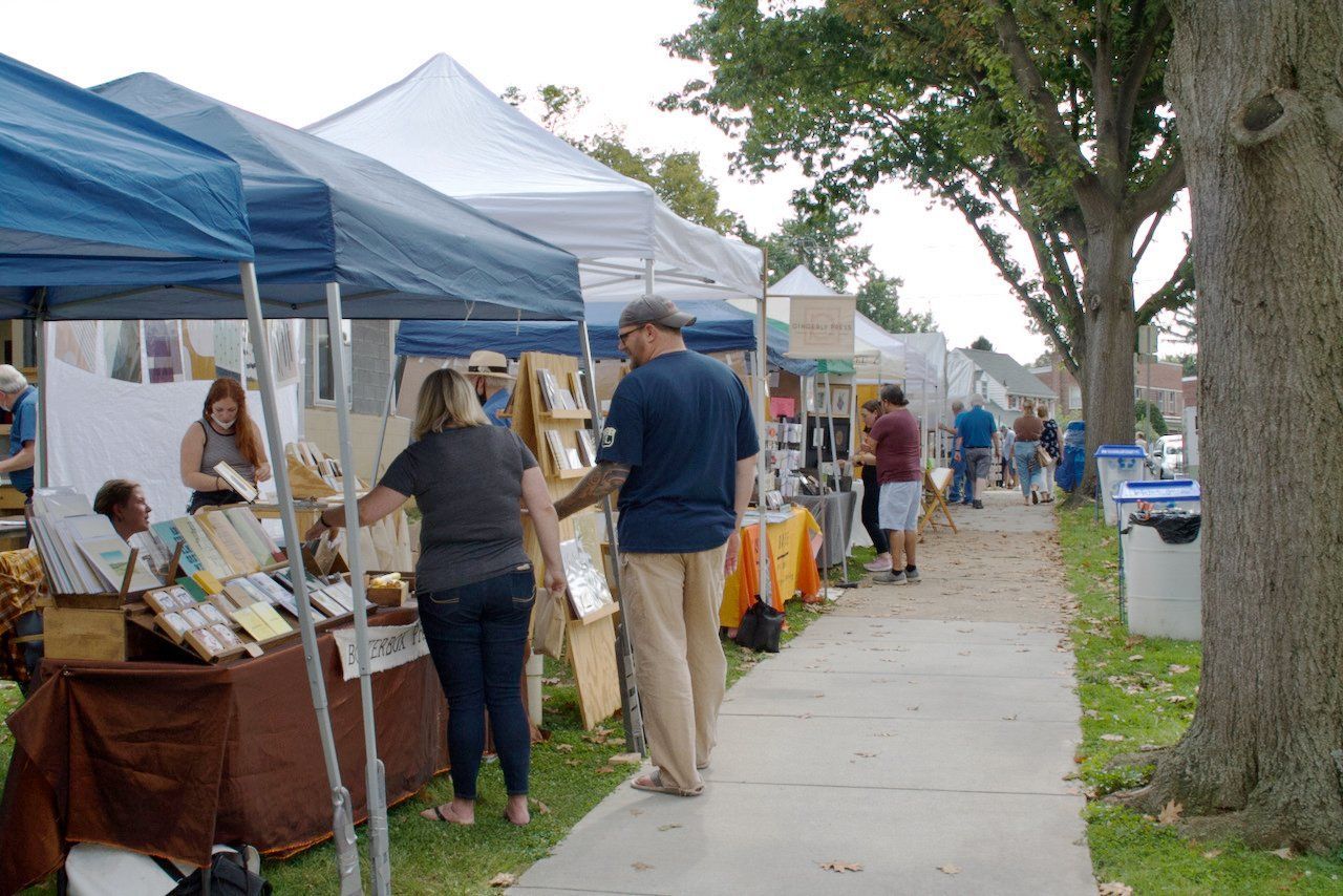 A group of people are walking down a sidewalk at a market.