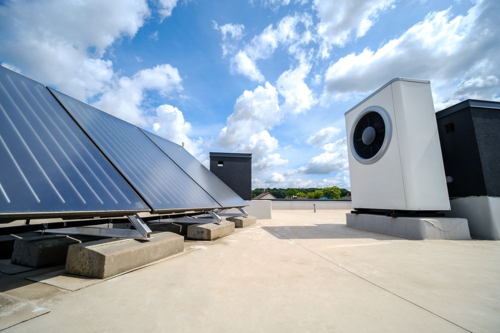 Solar panels and HVAC equipment on a rooftop under a partly cloudy sky.