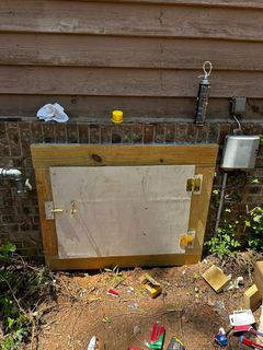 Wooden framed access door built into a brick wall. The door is metal.