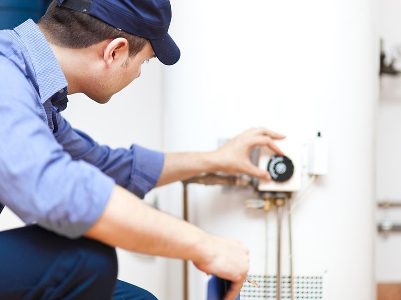 Man Fixing Water Heater - New Castle, PA - Central Heating & Plumbing