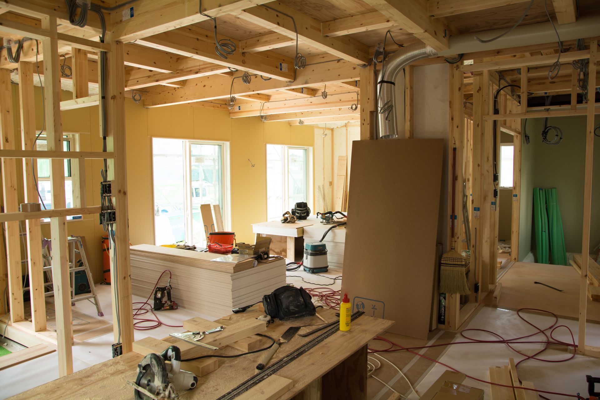 Interior of a room under construction, with exposed wooden framing and tools scattered around.