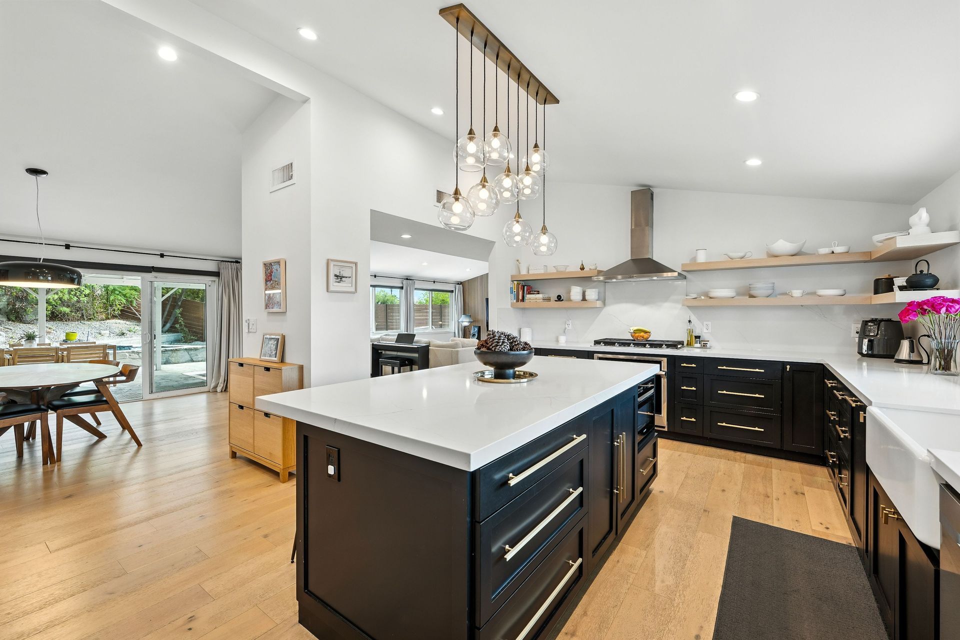 Modern kitchen with island, black cabinets, white countertops, and wood floors.