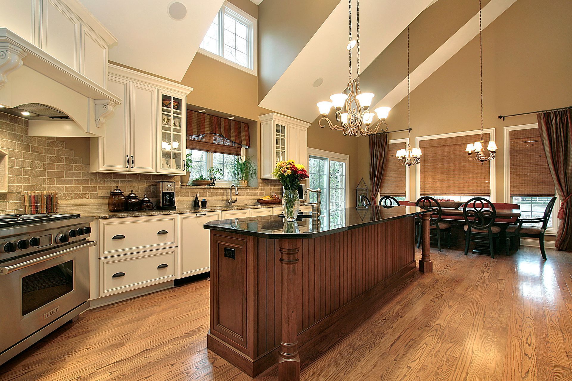 Spacious kitchen with wood floors, island, white cabinets, and dining area.
