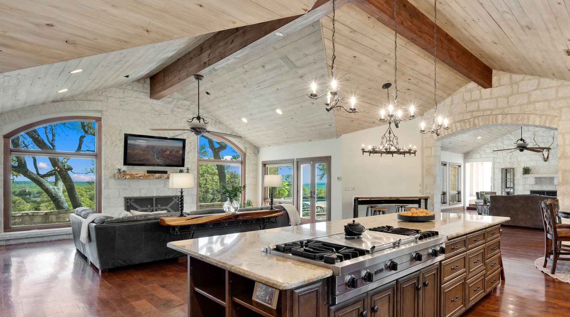 Spacious kitchen with a large island, wood beams, and a view of trees.