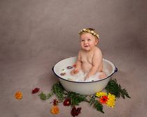 One year old baby girl in a milk bath with flowers