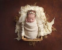 Newborn baby girl swaddled in cream blanket