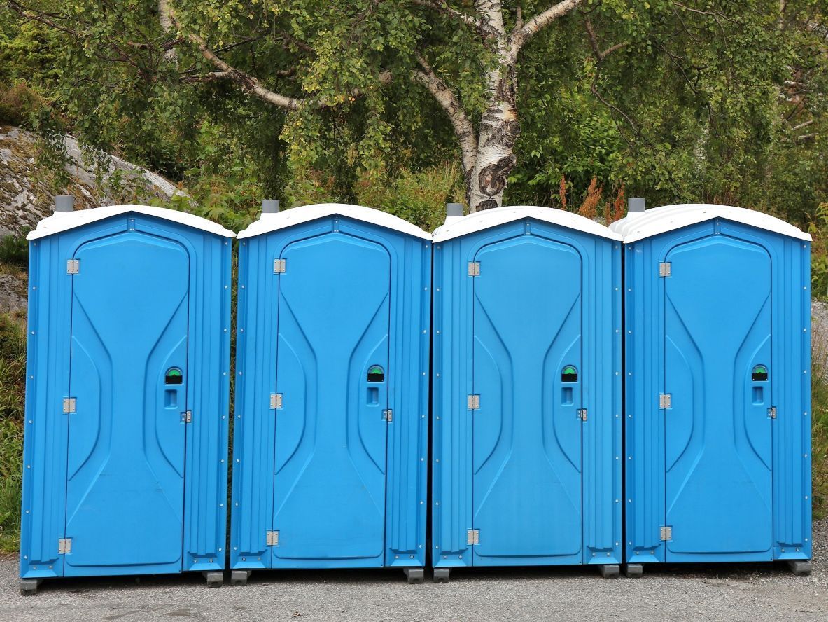 A row of blue portable toilets are lined up in a row.