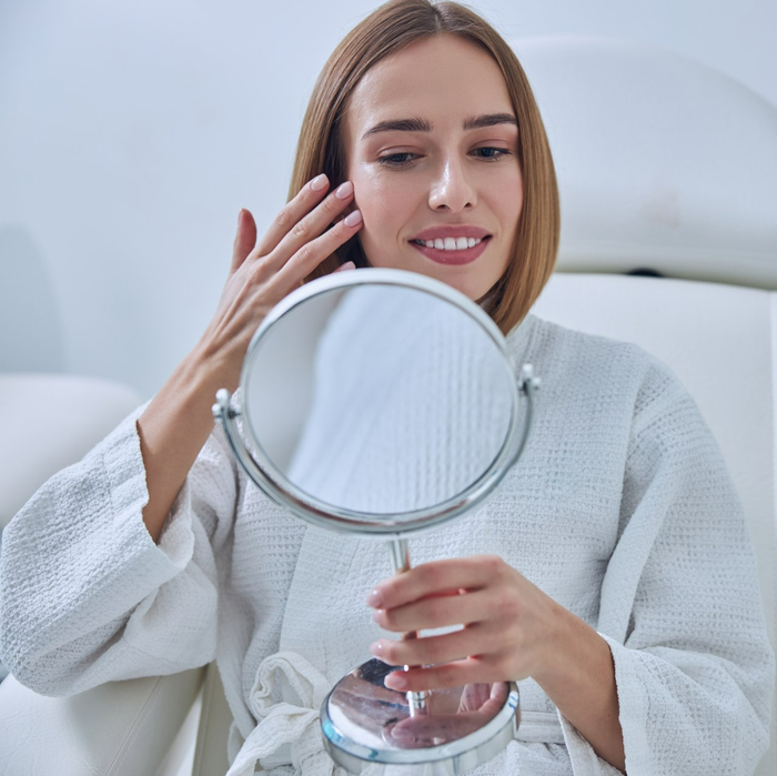 Attractive young female looking at a mirror enjoying professional advanced skin service