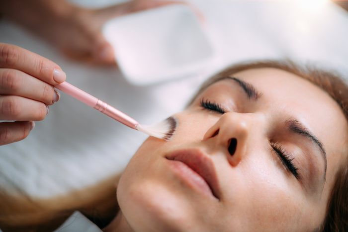A woman lying down with her eyes closed getting a Chemical Peel treatment