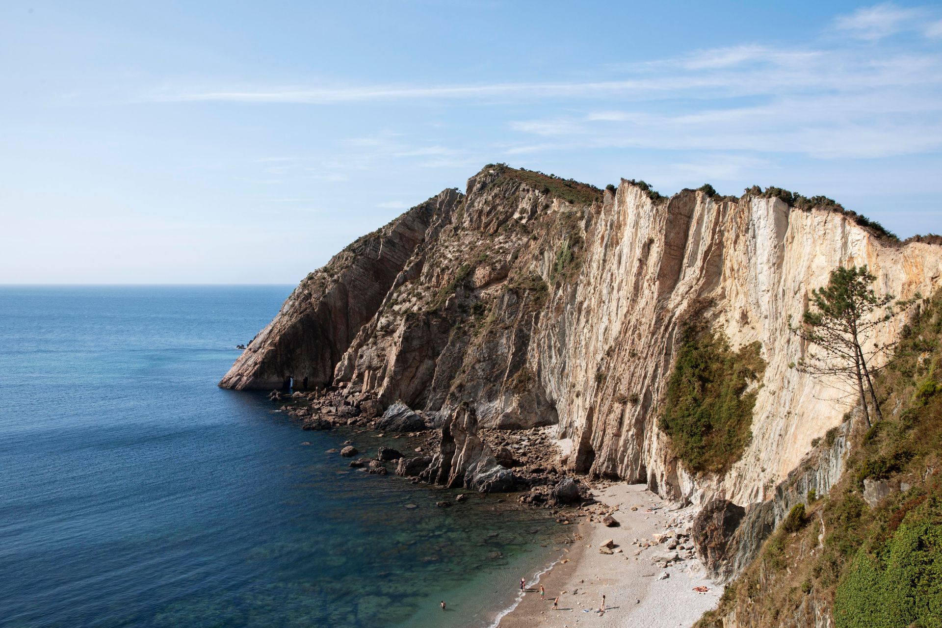 A cliff overlooking the ocean with a beach in the foreground.
