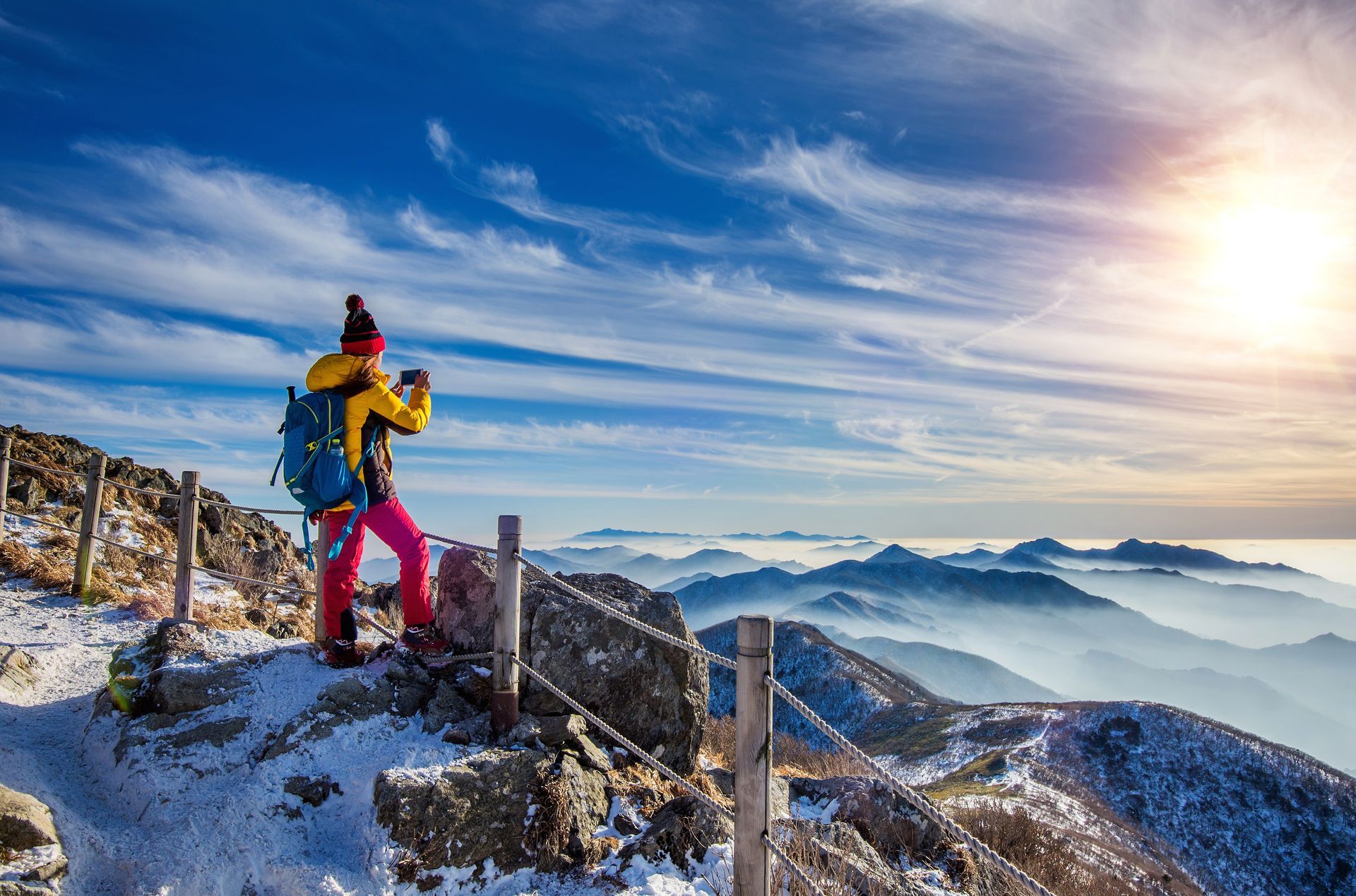 A person with a backpack is standing on top of a snow covered mountain.