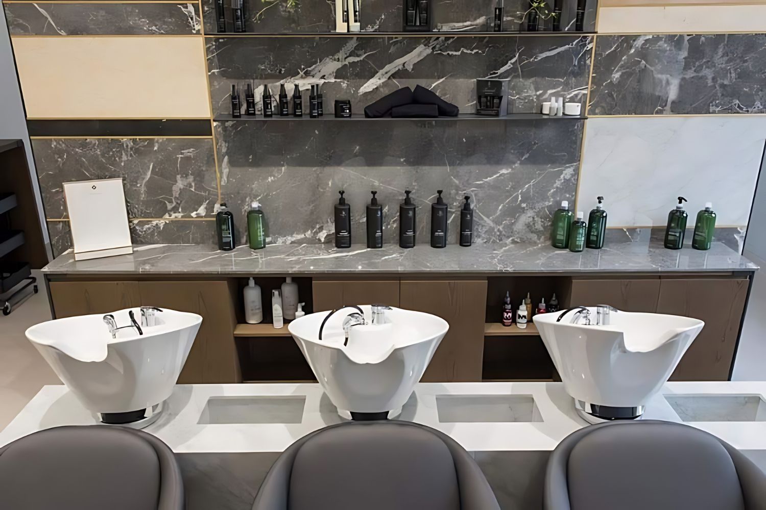 un parrucchiere con tre lavandini e bottiglie sugli scaffali.