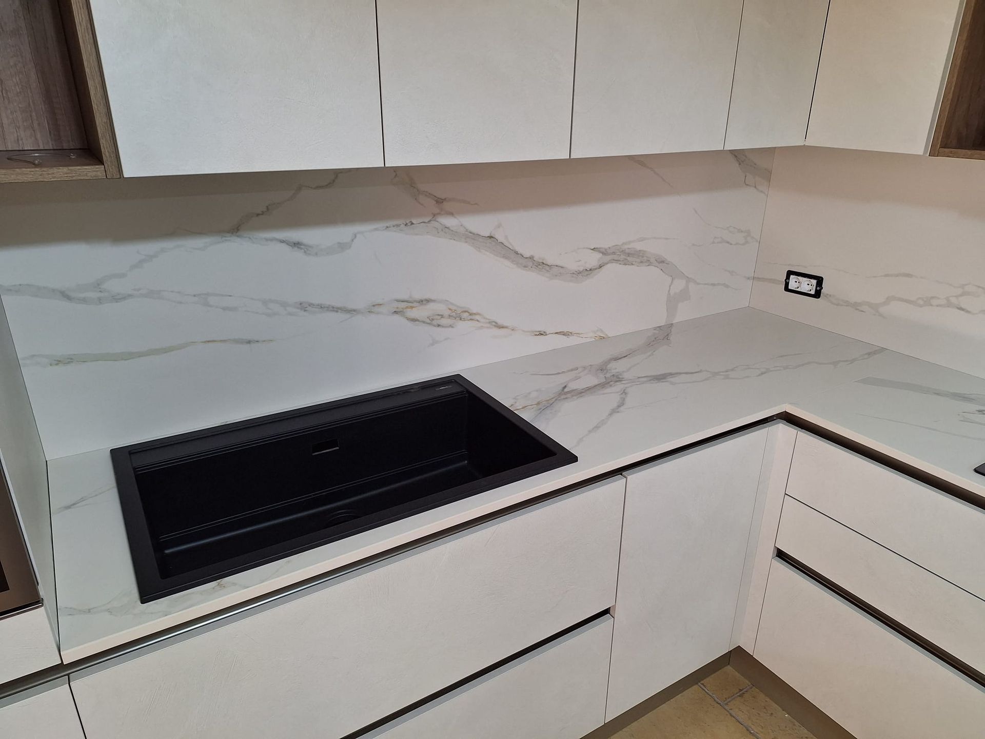 una cucina con mobili bianchi e un lavandino nero