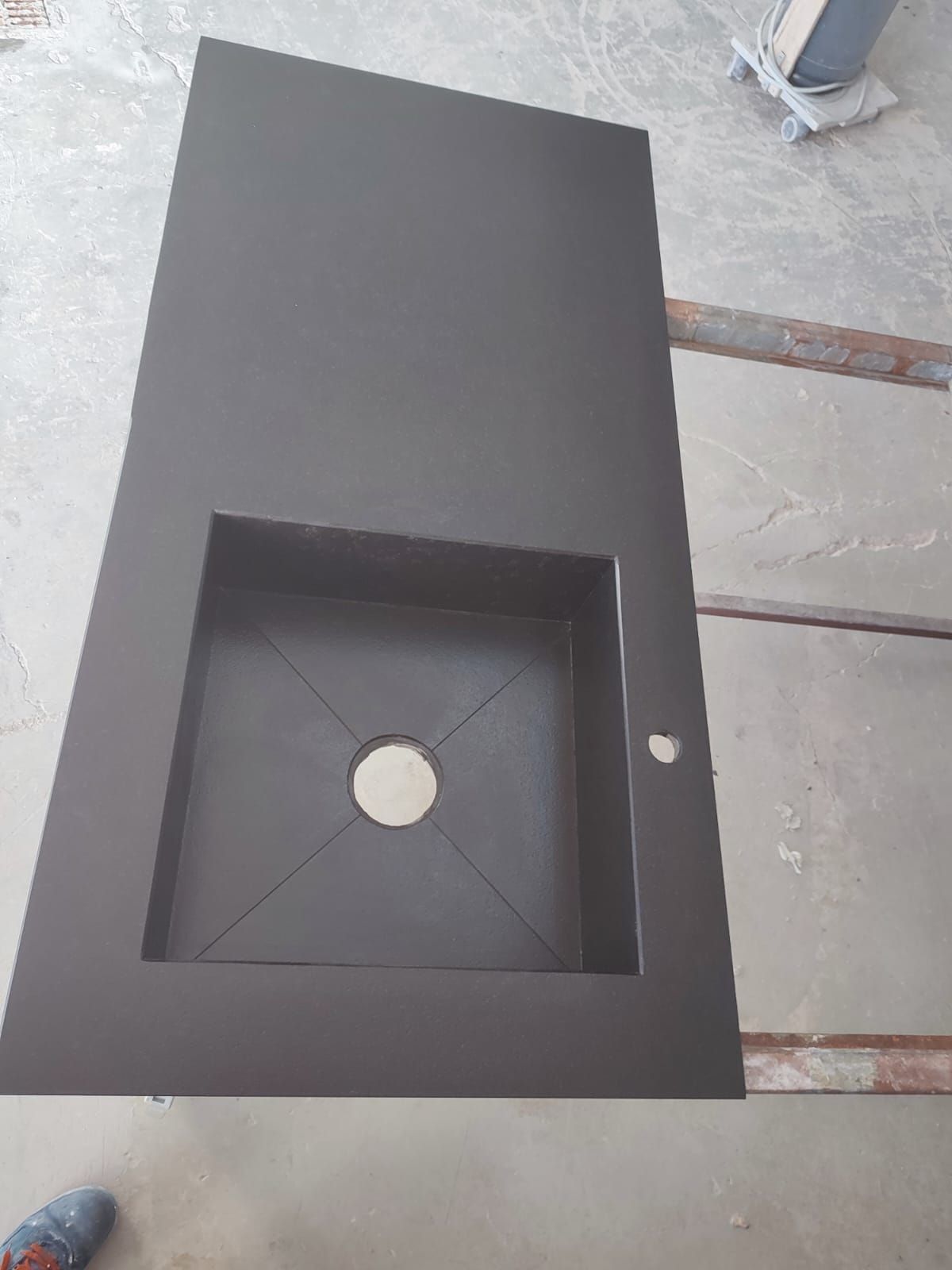 un lavello da cucina nero è appoggiato su un bancone di cemento.