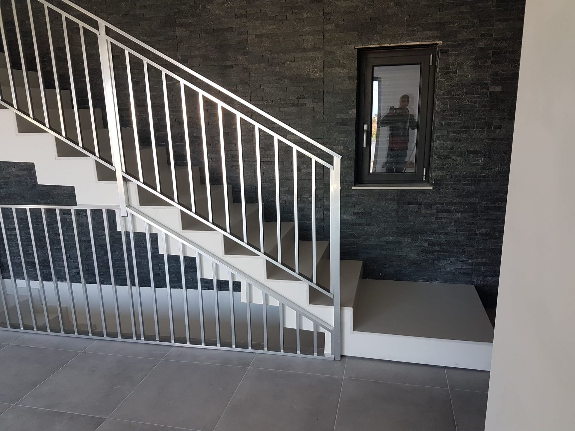 una scala con ringhiera in metallo e uno specchio a parete.