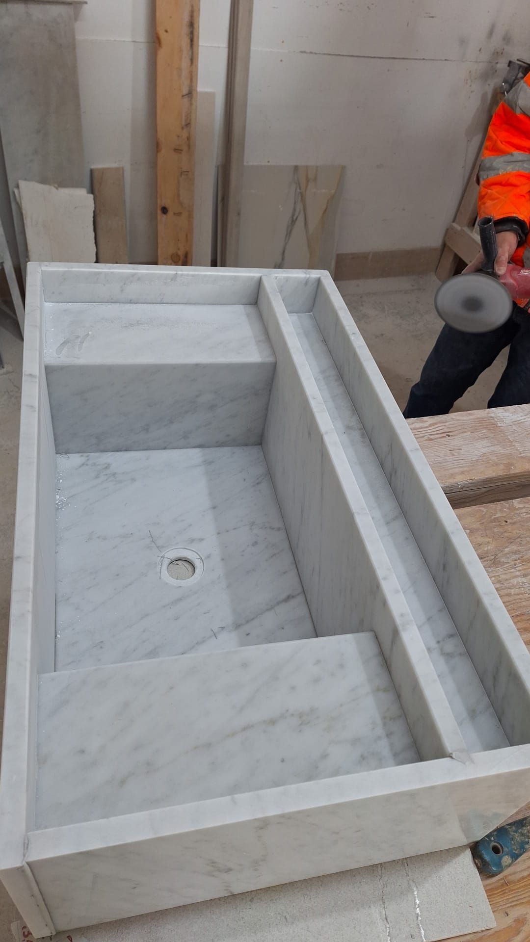 un grande lavandino in marmo è appoggiato sopra un tavolo di legno.