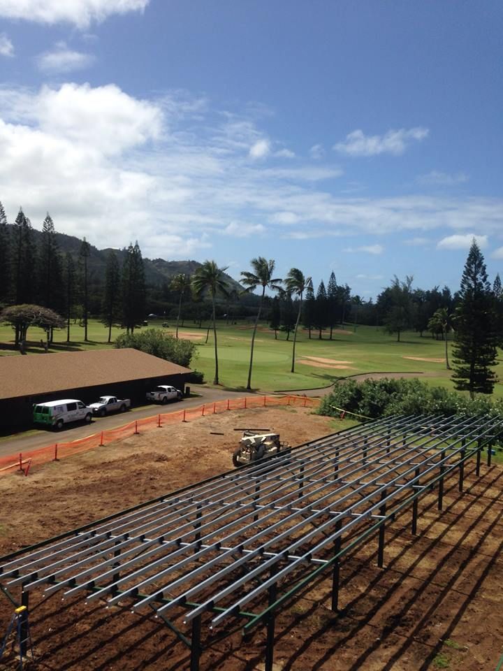 A row of solar panels are being installed in front of a golf course.