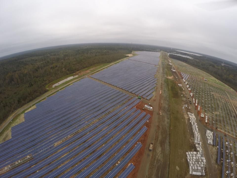 An aerial view of a large solar farm in the middle of a forest.