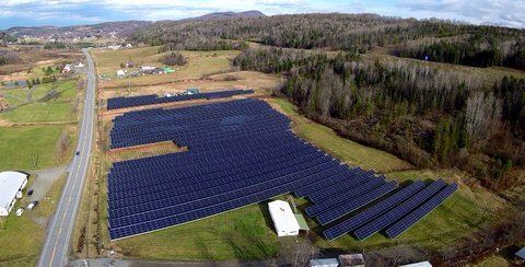 An aerial view of a large solar farm in the middle of a field.