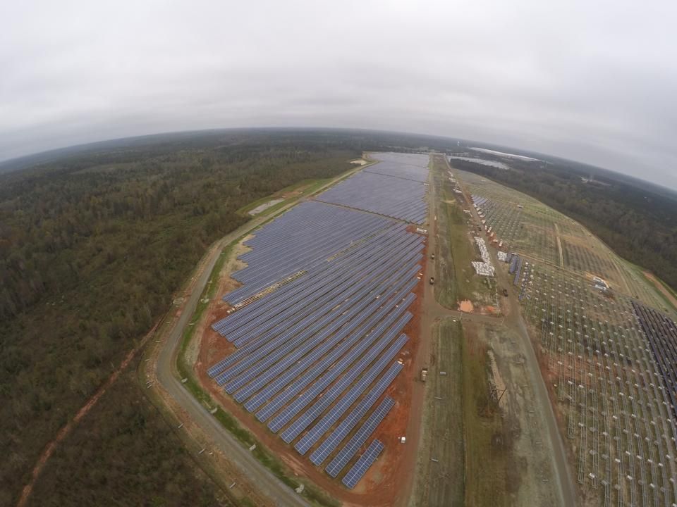 An aerial view of a large solar farm in the middle of a forest.