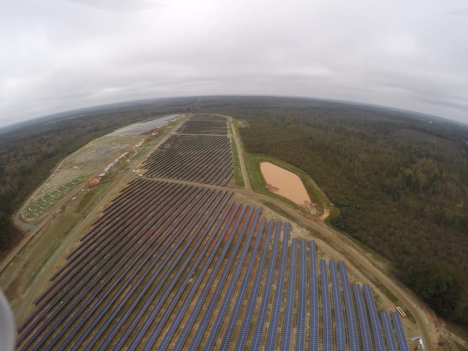 An aerial view of a large solar farm in the middle of a forest.