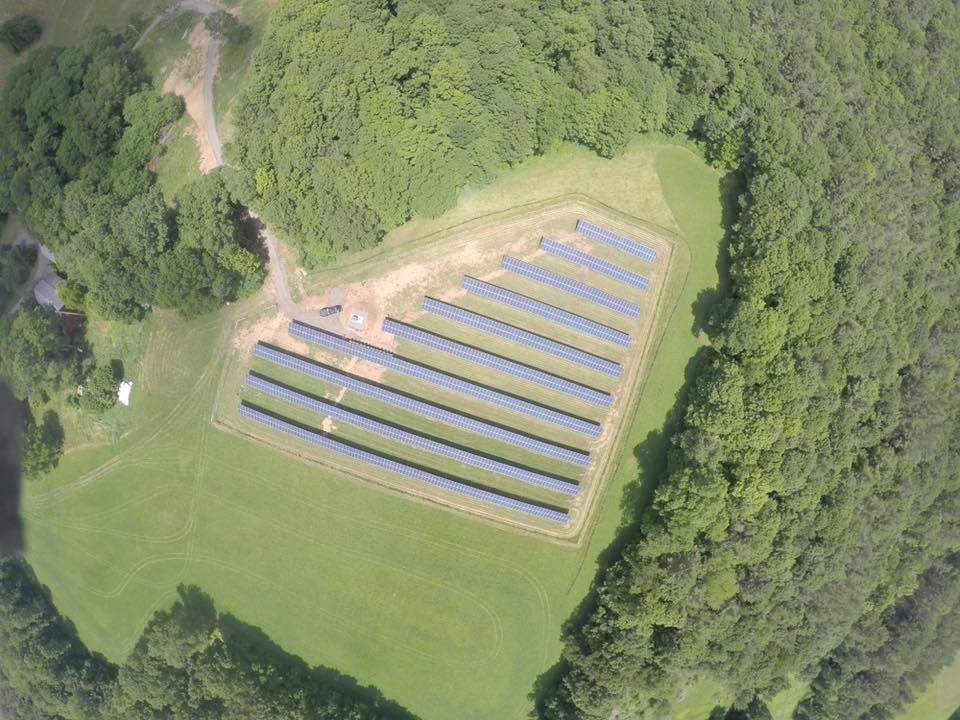 An aerial view of a field of solar panels surrounded by trees.