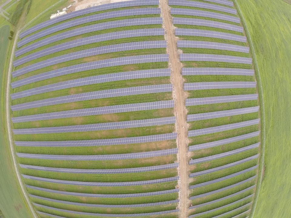 An aerial view of a field filled with rows of solar panels.