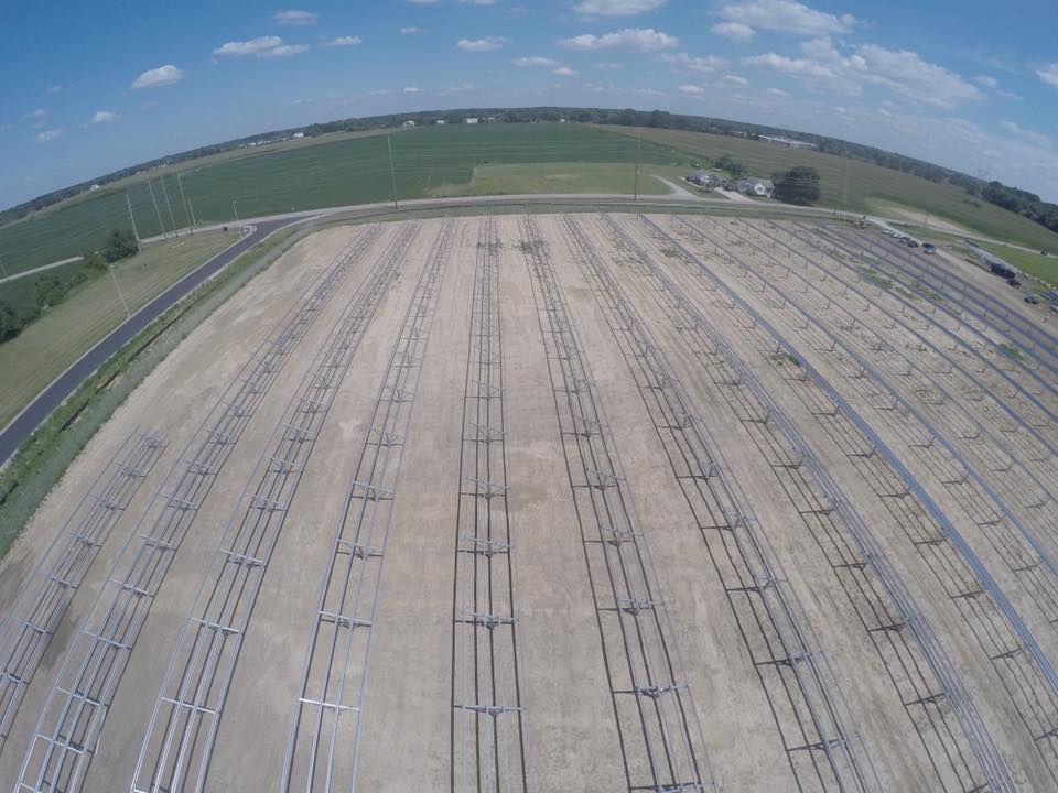 An aerial view of a large field with rows of solar panels.