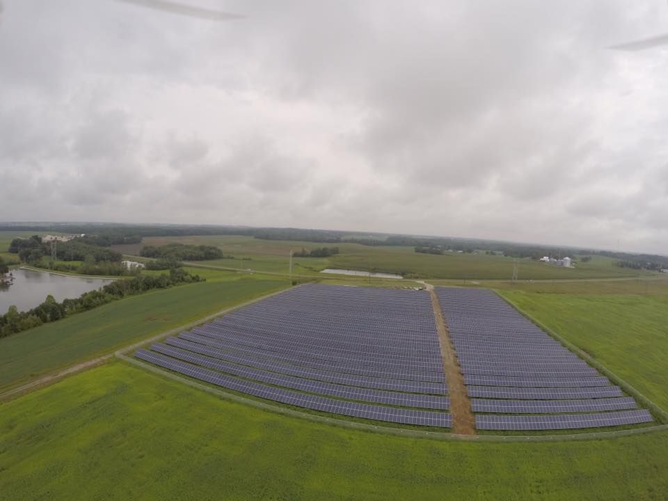 An aerial view of a field of solar panels on a cloudy day.