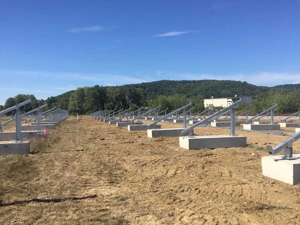 A row of solar panels sitting on top of a dirt field.