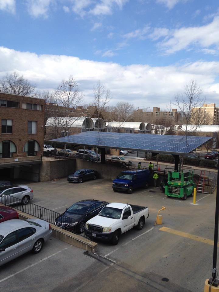 A white truck is parked under a solar roof in a parking lot