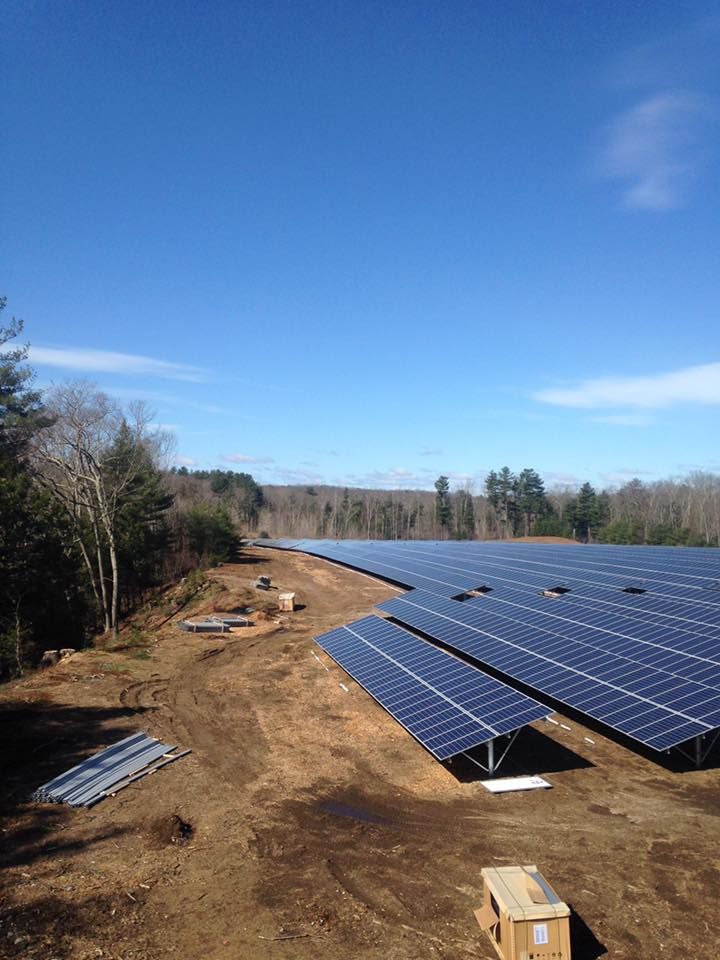 A large field of solar panels sitting on top of a dirt field.