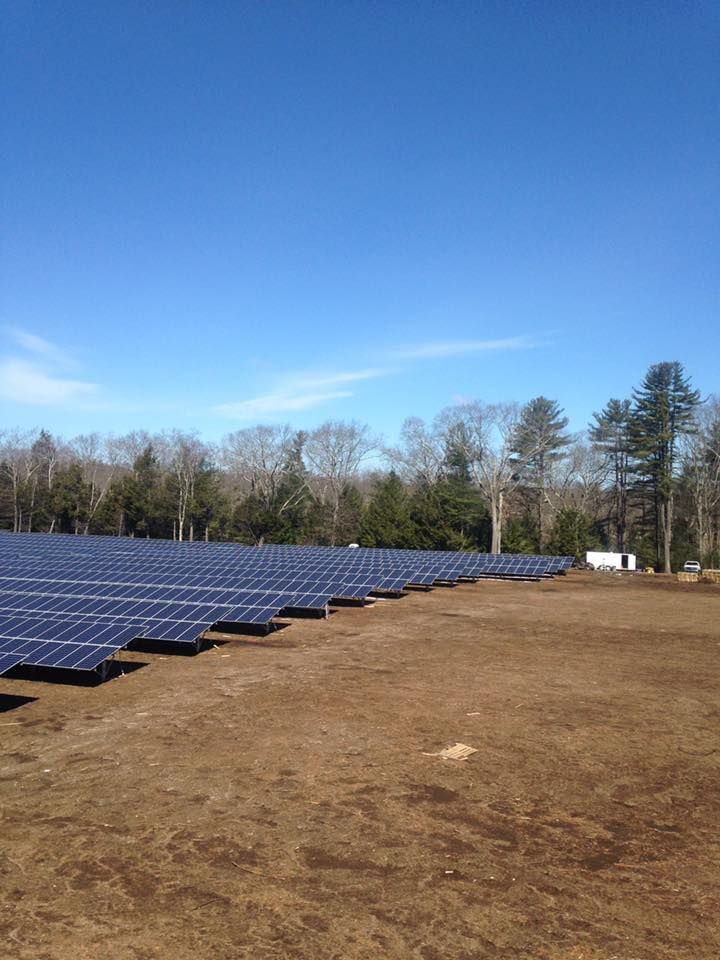 A large field of solar panels sitting on top of a dirt field.