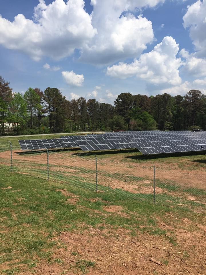 A field of solar panels sitting on top of a dirt field.